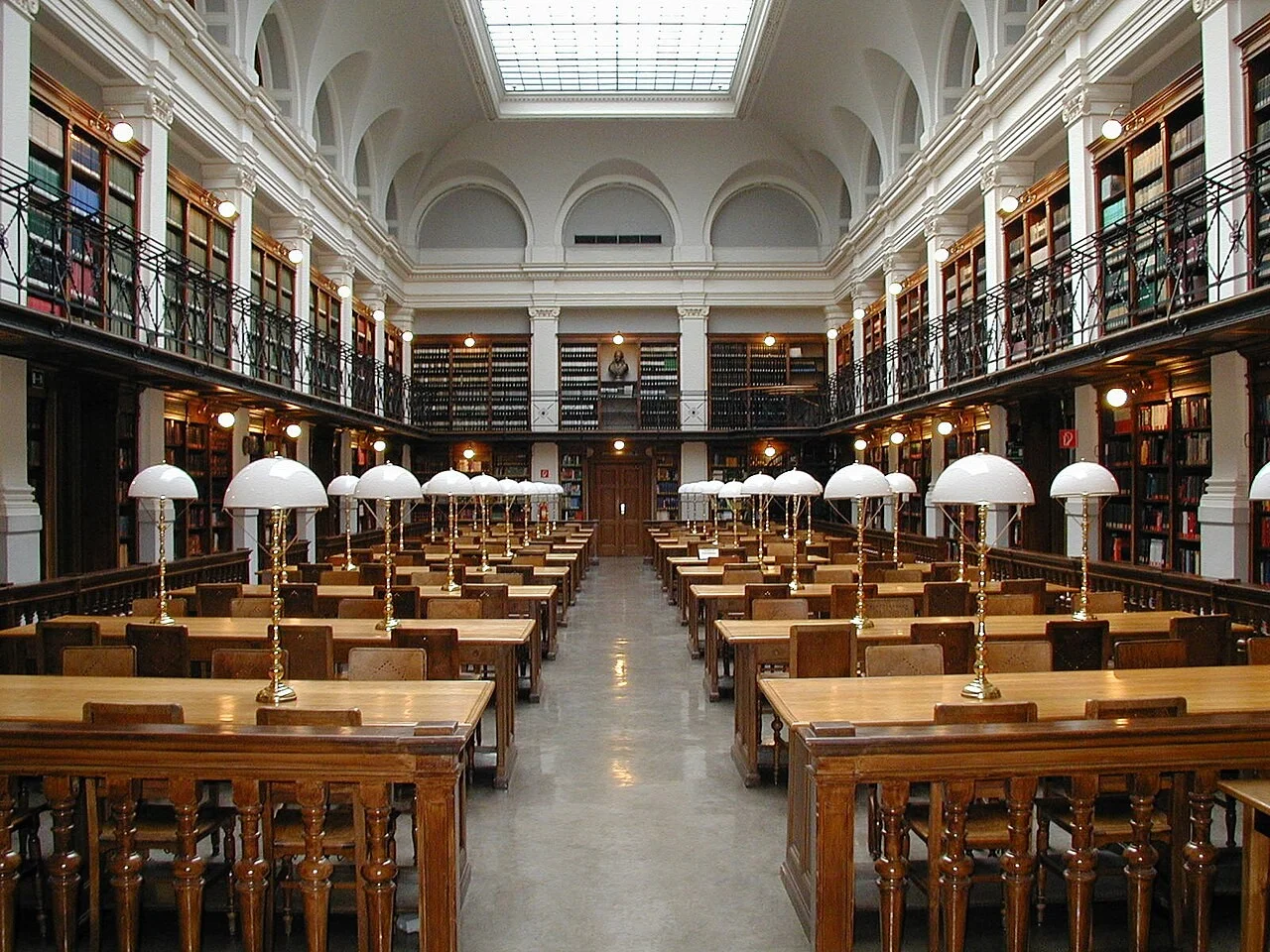 Sala de leitura de biblioteca universitária histórica com estudantes concentrados em estudos individuais
