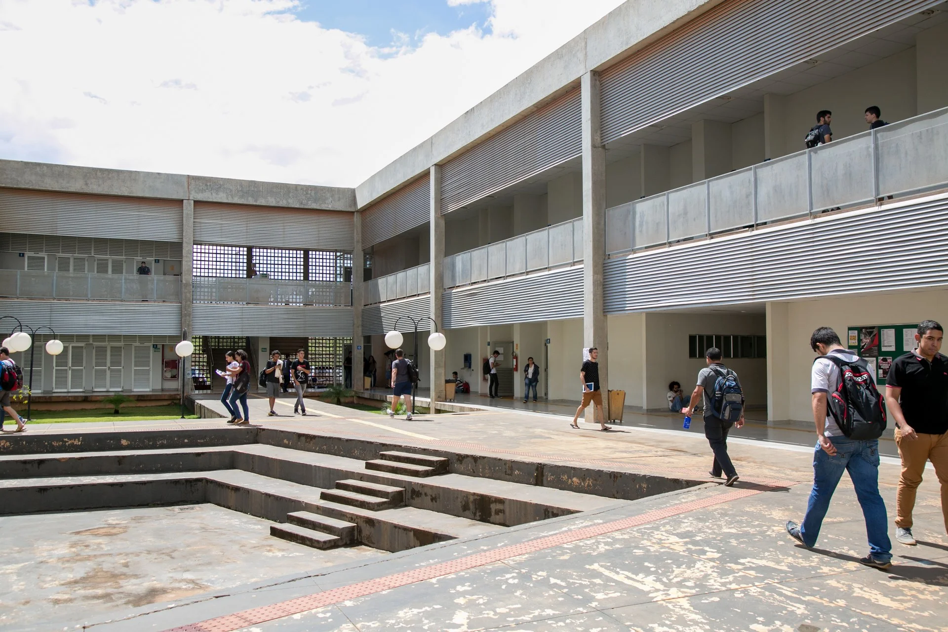Prédio acadêmico moderno no campus universitário com árvores e estudantes