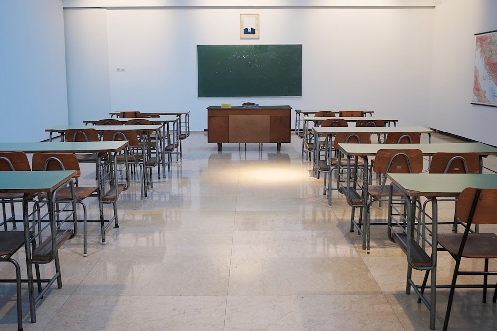 Entrada principal de prédio escolar urbano com escadaria e portas monumentais