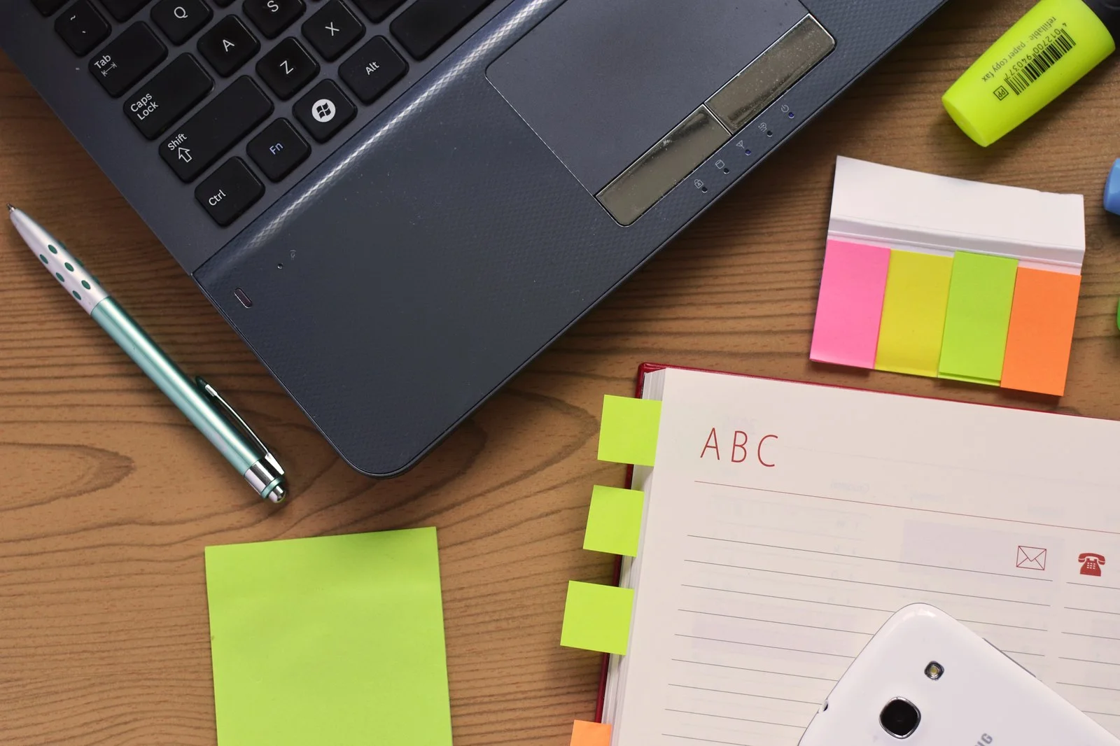 Mesa de estudos com computador portatil e caderno aberto para aplicacao do metodo interleaving