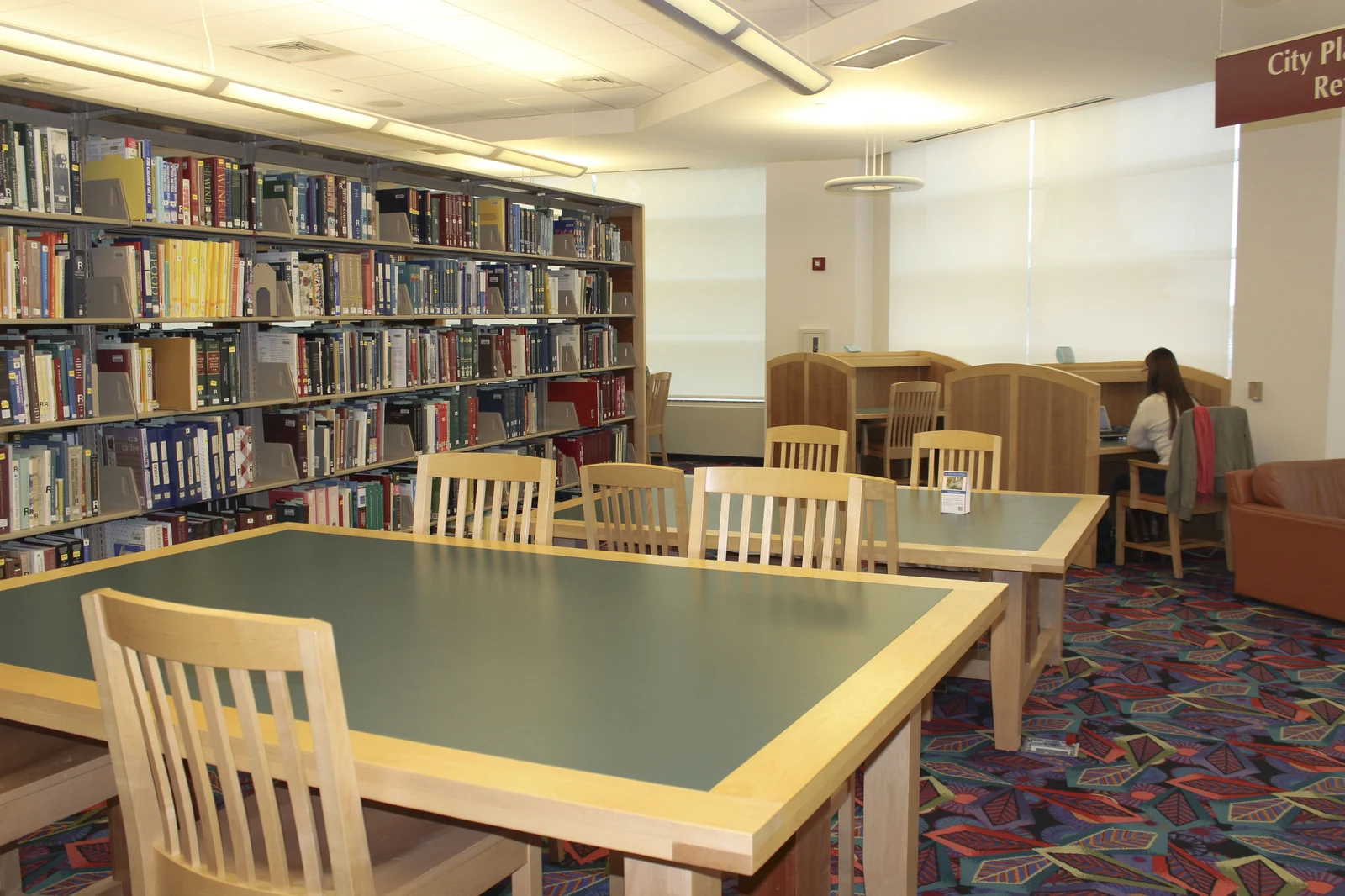 Estudante lendo livros e artigos acadêmicos na biblioteca universitária