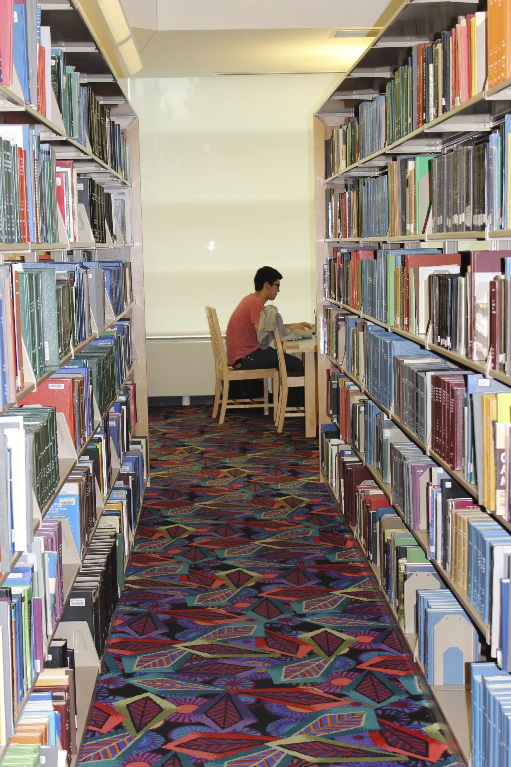 Estudante concentrado lendo em mesa de biblioteca silenciosa sem distrações eletrônicas