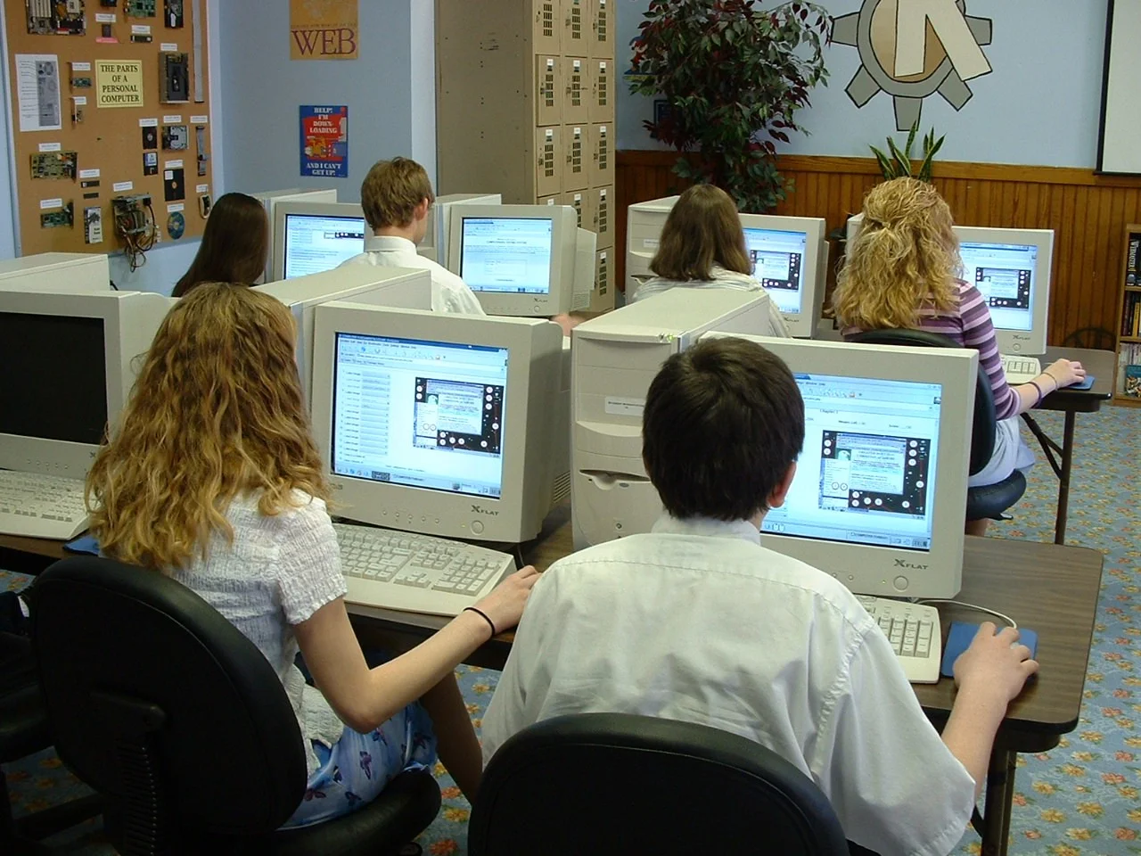 Estudantes em sala de informática realizando testes práticos e resolução de questões de avaliação