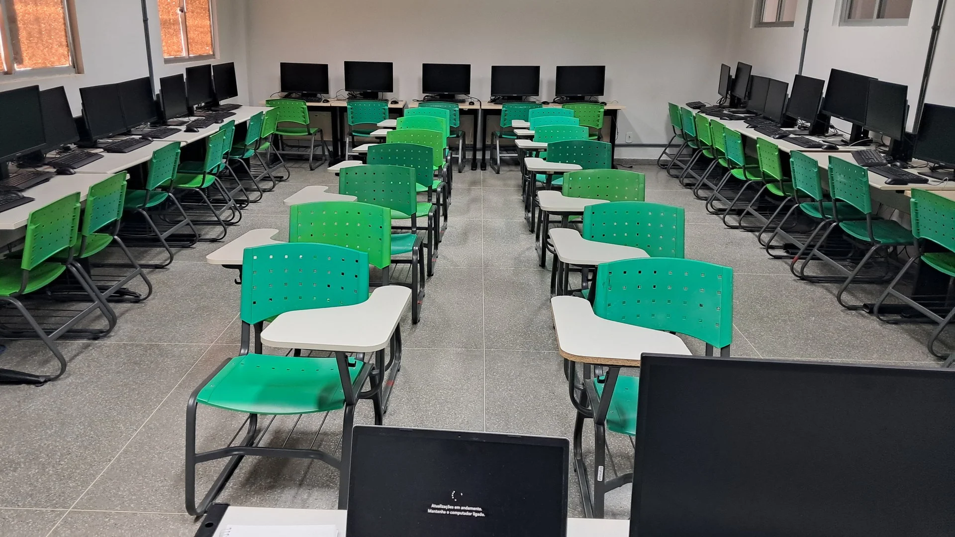 Fileiras de computadores modernos em laboratório educacional de informática