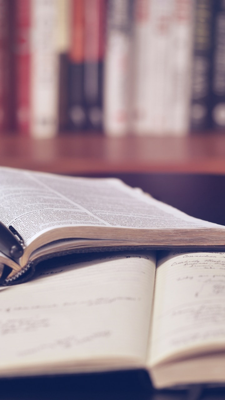Candidato redigindo resposta manuscrita para as questões discursivas do CACD com livros de apoio ao redor