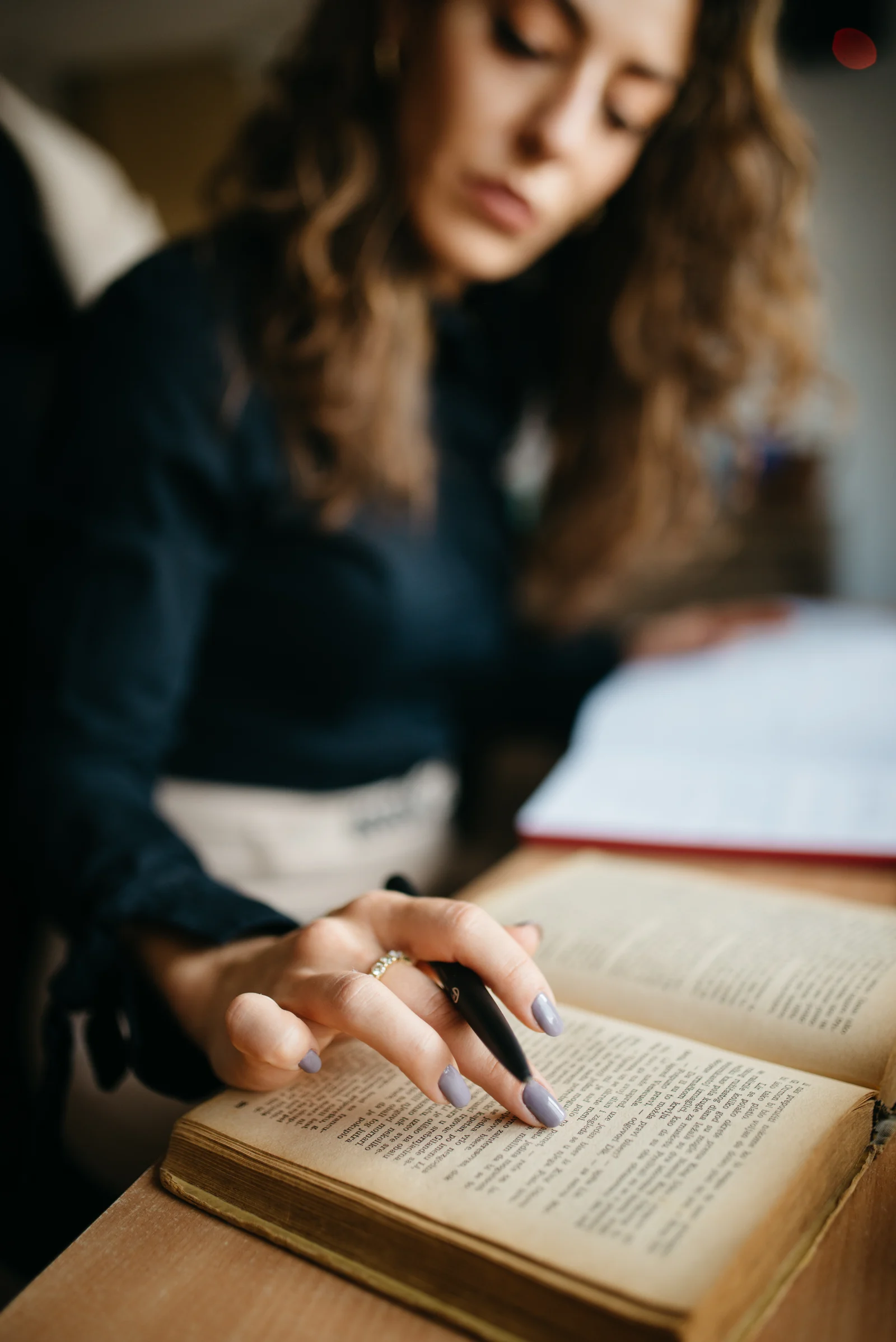 Estudante realizando anotações e leitura atenta em mesa de madeira