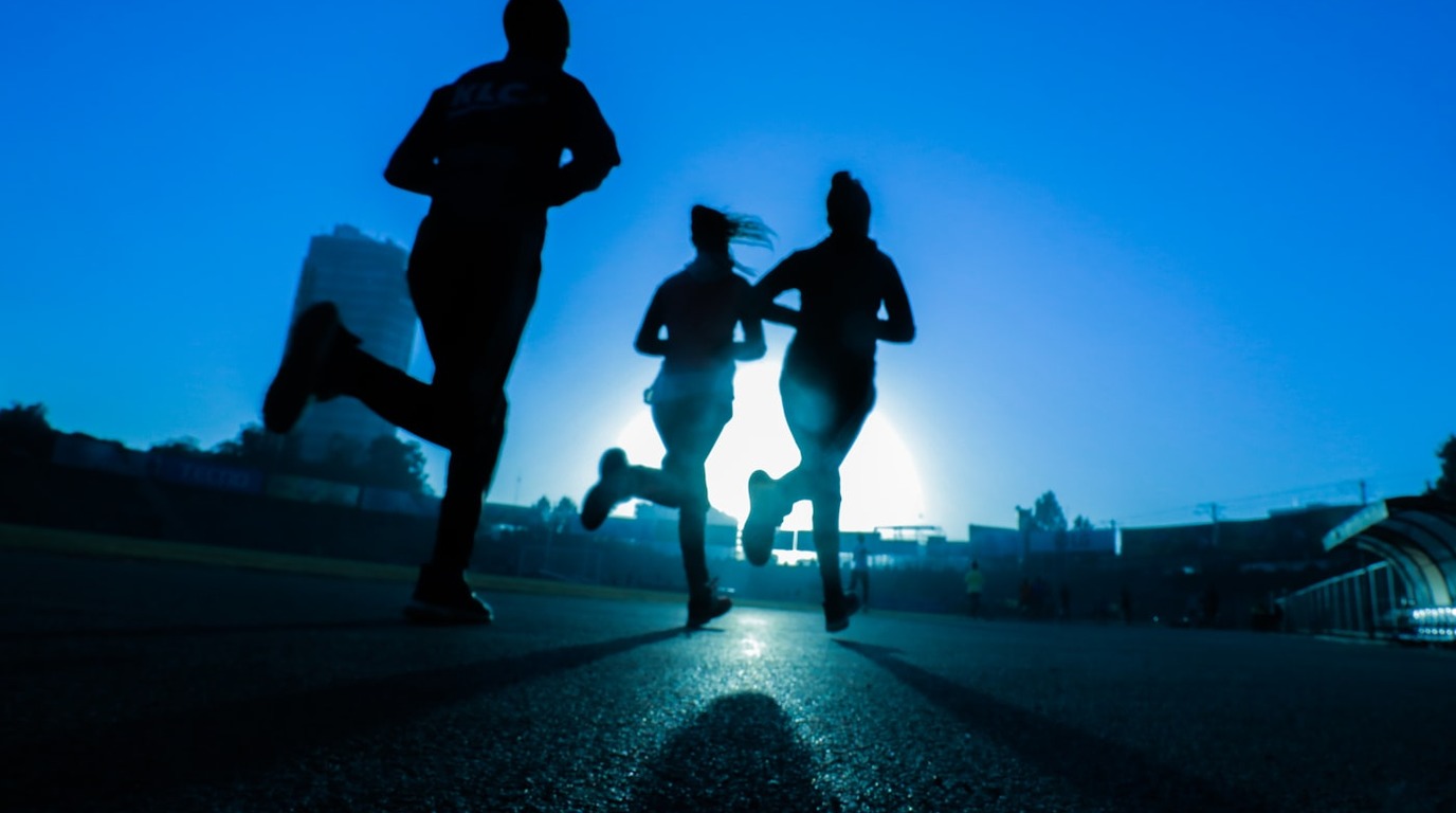 Atletas e candidatos correndo em pista de atletismo para preparação do teste de corrida de 12 minutos