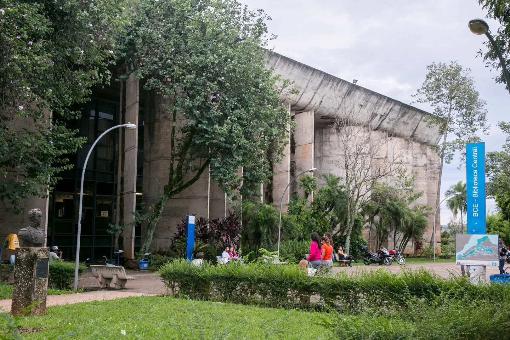 Fachada ampla da Biblioteca Central com painéis de concreto e espaço aberto de circulação acadêmica