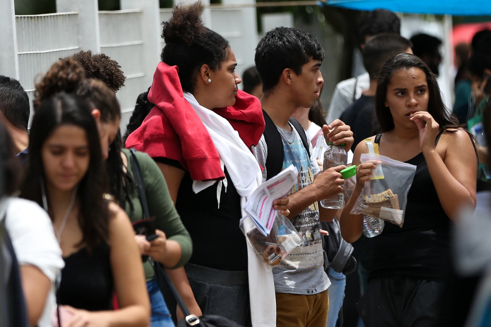 Candidatos realizando prova escrita de concurso público em carteiras escolares