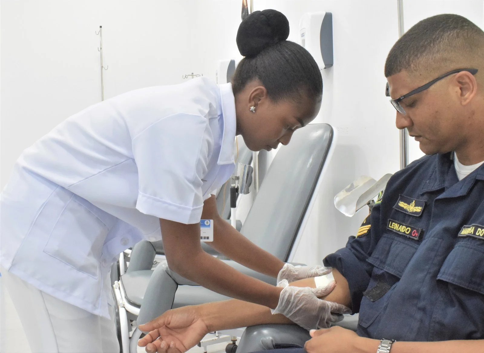 Enfermeira realizando procedimento técnico de assistência à saúde em ambiente hospitalar